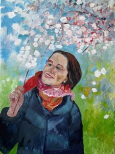Halbfiguriges Portrait von Annette mit Zweig vor einem blühenden Kirschbaum